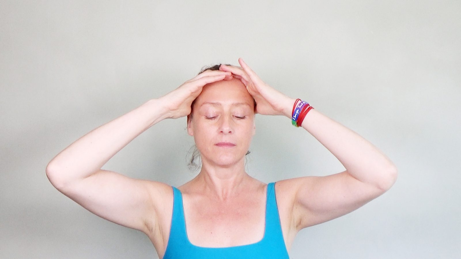 Hanna Sahlman practising Face Yoga with her eyes closed, both hands resting along her hairline and forehead.