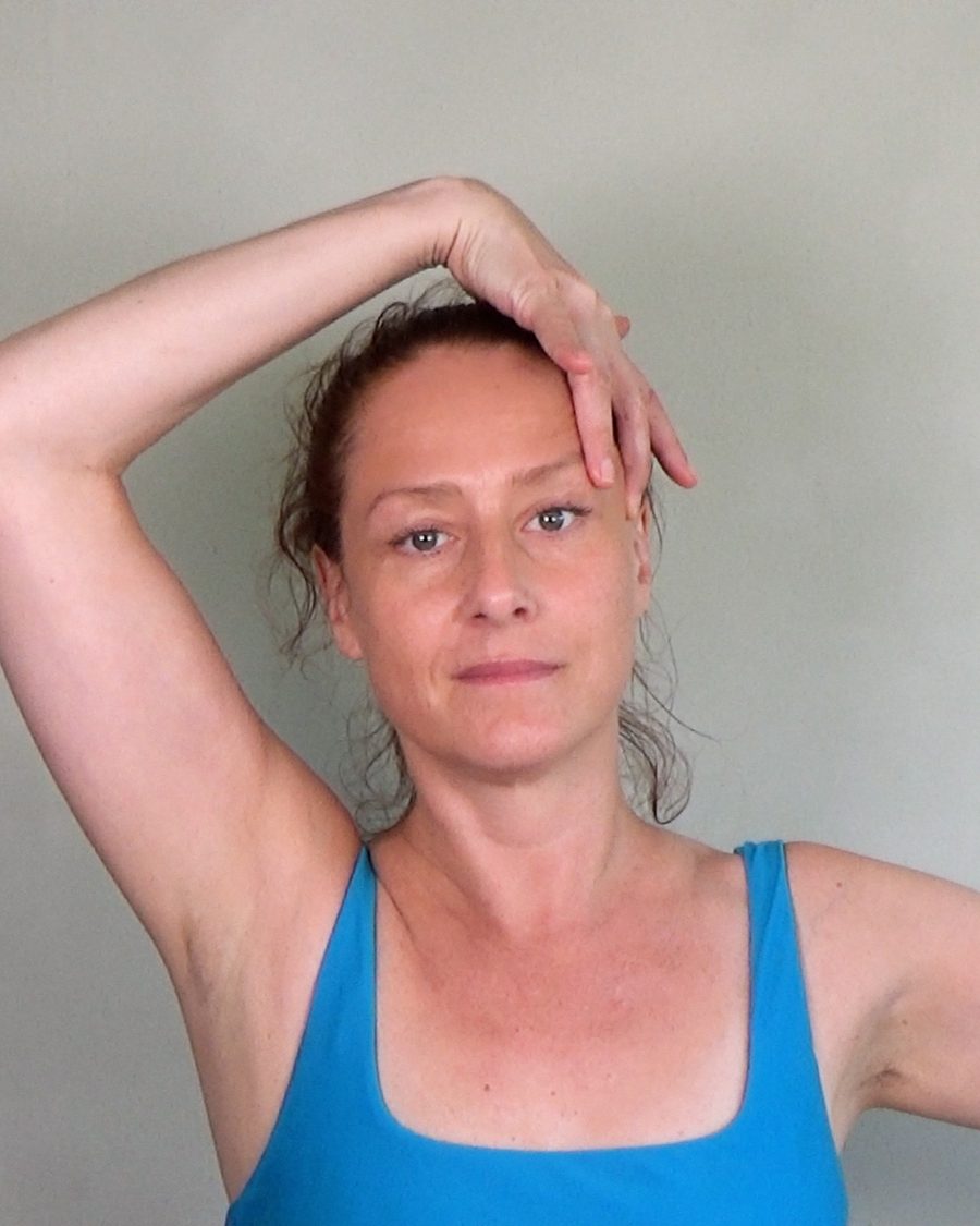 Hanna Sahlman practising Face Yoga, one hand resting along her hairline, looking directly at the camera.